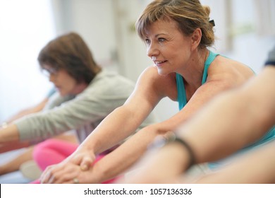 Portrait Of Senior Woman In Fitness Class Exercising On Floor