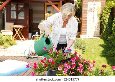 Portrait Of Senior Woman Gardening At Home. Retired Female Cares Of Plants While Standing In Her Beautiful Garden. 