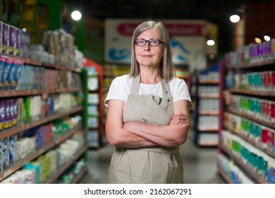 Portrait of senior woman in glasses manager of grocery store, supermarket. Standing in work clothes, arms crossed, looking at the camera, smiling - Powered by Shutterstock