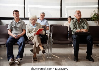 Portrait of senior woman with other people waiting for the doctor in hospital lobby