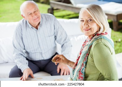 Portrait Of Senior Woman Playing Dominoes With Man At Nursing Home Porch