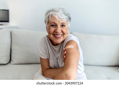 Portrait of a senior woman proudly showing her arm with bandage after getting vaccine. Mature white haired woman sitting against bright background after receiving coronavirus vaccination, thumbs up. - Powered by Shutterstock