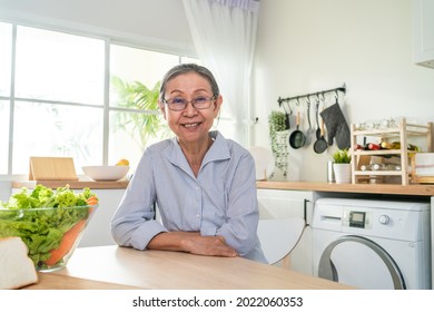 Portrait of Senior woman smile and look at camera in kitchen at home. Strong elderly older grandmother wear eyeglasses, feel happy and enjoy retirement life in house. Health care and medical concept. - Powered by Shutterstock