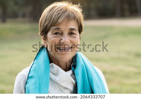 Portrait of senior woman smiling on camera after workout sport session outdoor at city park - Focus on face