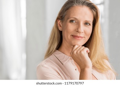 Portrait Of A Senior Woman Thinking With Hand On Chin And Looking Away. Mature Smiling Woman Feeling Happy. Thoughtful Retired Woman Planning Her Future. Vision Concept. 