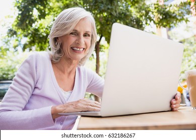 Portrait of senior woman using laptop in outdoor cafÃ© - Powered by Shutterstock