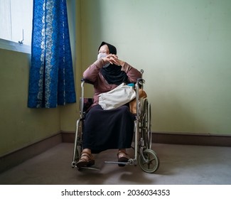 Portrait Of A Senior Woman Wearing Hijab On Wheelchair In A Hospital.