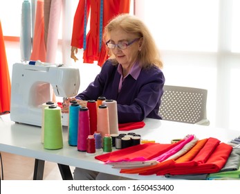 Portrait Of Senior Woman Working As Professional Seamstress Sewing. Female Older Fashion Designer Has Long Term Experience With Creative Dressmaking Business. Active Elderly 70s Needlewoman Lifestyle.