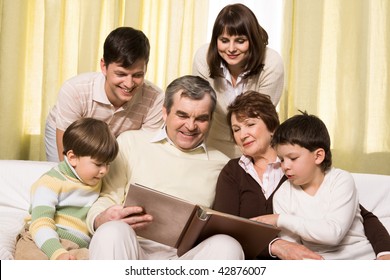 Portrait Of Senior And Young Couples With Their Children Looking At Family Photos