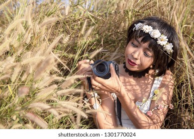 Portrait of a sensual Young photographer girl taking photos outdoor with wearing flowers crown on her head. Spring on a sunny day grass flower field. - Shutterstock ID 1301770024