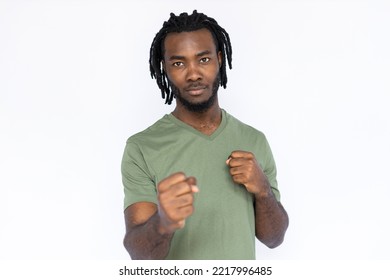 Portrait of serious African American man with clenched fists. Confident young male model with braided dark hair in green T-shirt looking at camera, ready to fight. Strength, self-defense concept. - Powered by Shutterstock