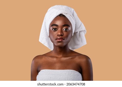 Portrait Of Serious African American Young Woman Posing In White Towel Looking At Camera Standing Isolated Over Studio Background. Female Headshot Of Black Lady. Sensuality And Natural Beauty Concept