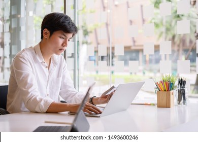 Portrait of a serious asian businessman thinking and concentrating typing on laptop at co-working spaces. Man laptop working concept