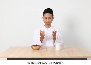 Portrait of serious Asian muslim man praying before eating sahur and breaking fast. Culture and tradition on Ramadan month. Isolated image on white background