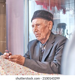 Portrait Of Serious Asian Senior Muslim Man Sitting At Table At Home