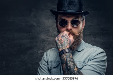 Portrait of serious, bearded male in sunglasses and cylinder hat.