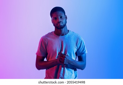 Portrait Of Serious Black Athlete In T-shirt Looking At Camera In Neon Light. Motivated Professional Sportsman Posing With Arms Folded On His Chest. Active Lifestyle, Bodybuilding Concept