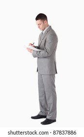 Portrait Of A Serious Businessman Taking Notes Against A White Background