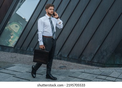 Portrait Of Serious Businessperson Dressed In Formal Attire Talking On Phone Outdoors.