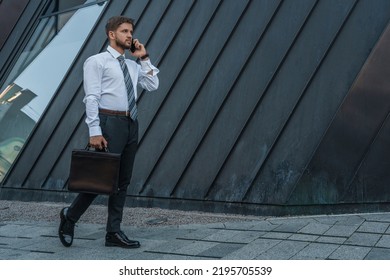 Portrait Of Serious Businessperson Dressed In Formal Attire Talking On Phone Outdoors.