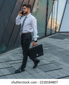 Portrait Of Serious Businessperson Dressed In Formal Attire Talking On Phone Outdoors.