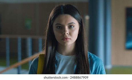 Portrait serious calm sad upset Caucasian student girl female schoolgirl woman pupil teenager teen teenage generation in school corridor in university college hall education study looking at camera - Powered by Shutterstock