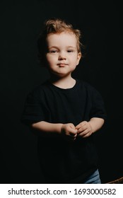 Portrait Of A Serious Caucasian Child Boy On A Dark Background