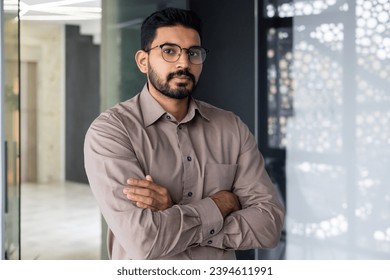 Portrait of serious confident hindu businessman, man in shirt thinking and looking at camera with crossed arms, mature boss working inside office at workplace, financier accountant in glasses. - Shutterstock ID 2394611991