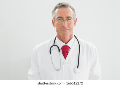 Portrait Of A Serious Confident Male Doctor Standing Over White Background