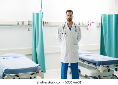 Portrait of a serious doctor in charge of the emergency room, standing in front of a couple of empty beds