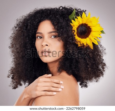 Portrait, serious or face of black woman with sunflower in hair in studio for spring time, luxury spa or self care. Aesthetic, beauty facial or girl model with plant for skincare, cosmetic or makeup