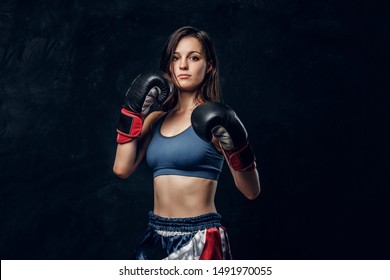 Portrait Of Serious Female Boxer In Boxing Gloves And Sportive Wear At Dark Photo Studio.