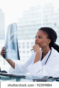 Portrait Of A Serious Female Doctor Looking At A Set Of X-rays In Her Office