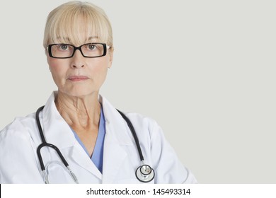 Portrait Of Serious Female Doctor With Stethoscope Around Neck Over Gray Background