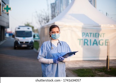 Portrait Of Serious Female Key Front Line Worker In Blue PPE Uniform,standing Outside EMS Hospital Or ICU Clinic Facility Entrance,UK COVID-19 Drive Through Testing Site,rt-PCR Coronavirus Diagnostic 