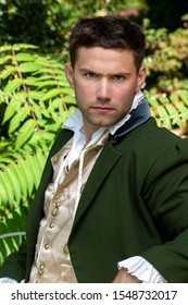 Portrait Of Serious Handsome Man Dressed In Vintage Costume Sitting On Bench In Garden