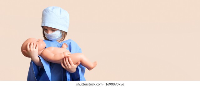 Portrait Of Serious Little Girl Dressed Up In Doctor Holds On Hands Baby Doll On Isolated Background /concept  Pediatric Emergency/obstetrics/abortion Protest/artificial Insemination