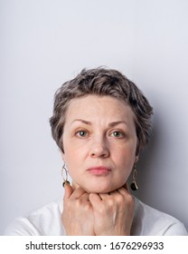 Portrait Of A Serious Looking Woman Of 40-50 With Graying Hair And No Make Up On Plain White Background, Vertical Image