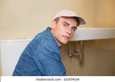 Portrait Of A Serious Male Plumber By The Sink At Bathroom