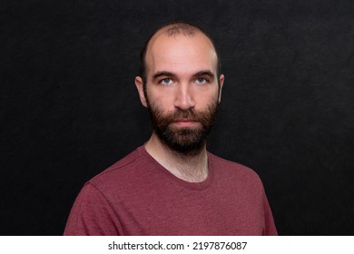 Portrait Of A Serious Man 30-35 Years Old In A T-shirt On A Black Background.