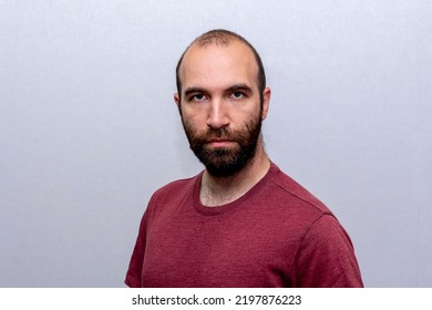 Portrait Of A Serious Man 30-35 Years Old In A T-shirt, Bald And With A Beard On A Light Background.