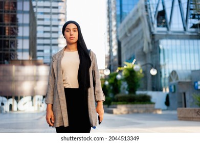 Portrait Of A Serious Muslim Woman Standing In A Urban Area Looking At Camera In A Sunny Day.