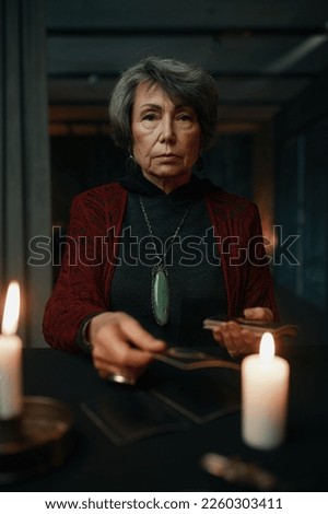 Portrait of serious old mature fortune teller with taro crads