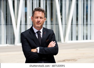 Portrait Of Serious Older Businessman Standing With Arms Crossed