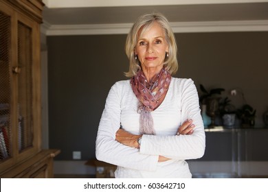 Portrait Of Serious Older Woman Standing In Study With Arms Crossed