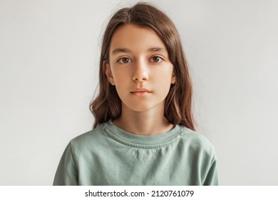 Portrait Of Serious Preteen Girl Standing Looking At Camera Over Gray Studio Background. Calm Kid Posing Wearing Casual Clothes, Headshot. Children Fashion Concept. Front View