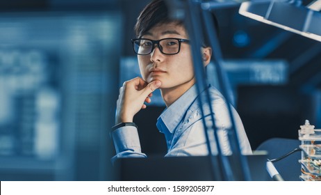 Portrait Of A Serious Professional Japanese Development Engineer Thinking At His Work Place In A High Tech Research Laboratory With Modern Computer Equipment.