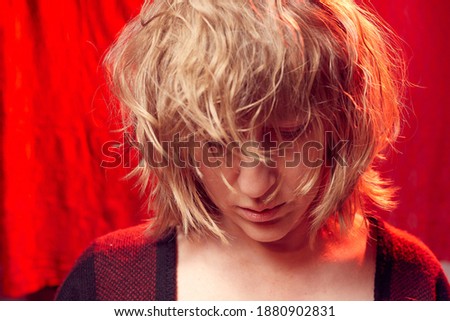 Portrait of serious sad tousled disheveled middle-aged woman on red background. Unprofessional female model in the Studio