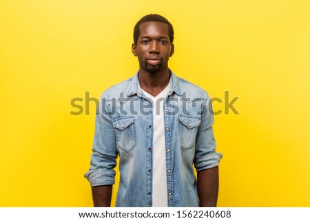 Portrait of serious self-assertive handsome man in denim casual shirt with rolled up sleeves looking smart and professional, freelancer or employee. indoor studio shot isolated on yellow background