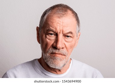 Portrait of a serious senior man in a studio, looking at camera.